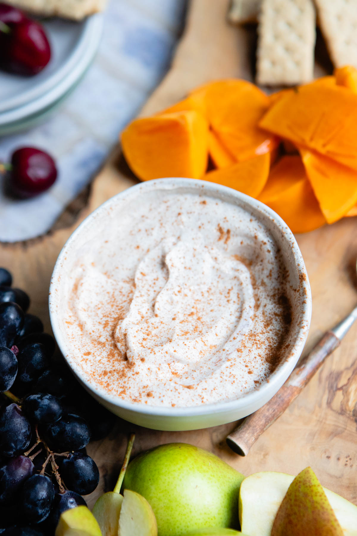blended Greek yogurt fruit dip in a small bowl next to a pile of delicious fruit