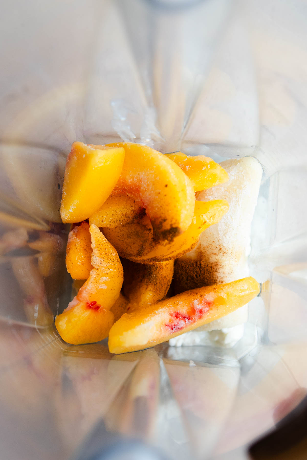 ingredients added to a blender to make a high protein peach cottage cheese smoothie