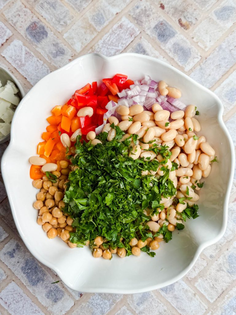 beans and fresh herbs added to a bowl of vegetables