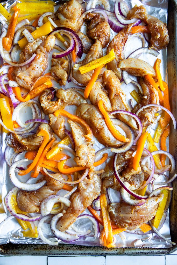 sheet pan covered in foil and lined with raw chicken fajitas ready to go in the oven