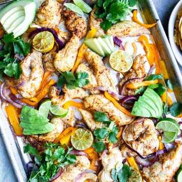 sheet pan chicken fajitas garnished with limes and cilantro