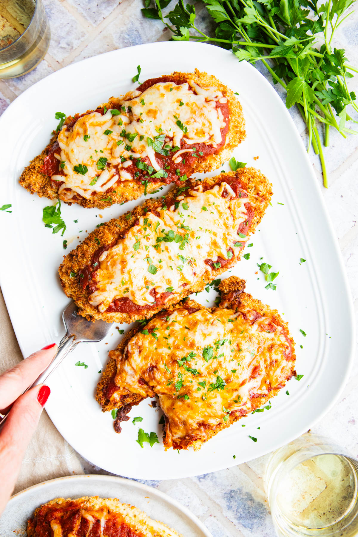 air fryer chicken parmesan on a white platter with parsley garnish 