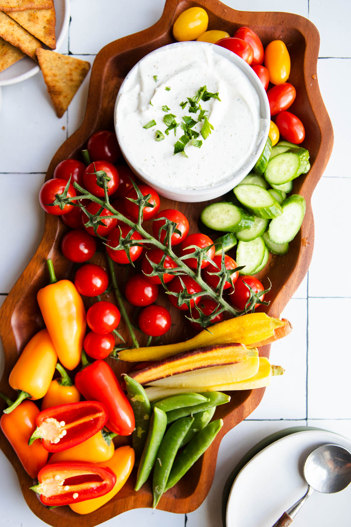 cottage cheese ranch dip in a white bowl set on a wood curvy platter filled with fresh veggies