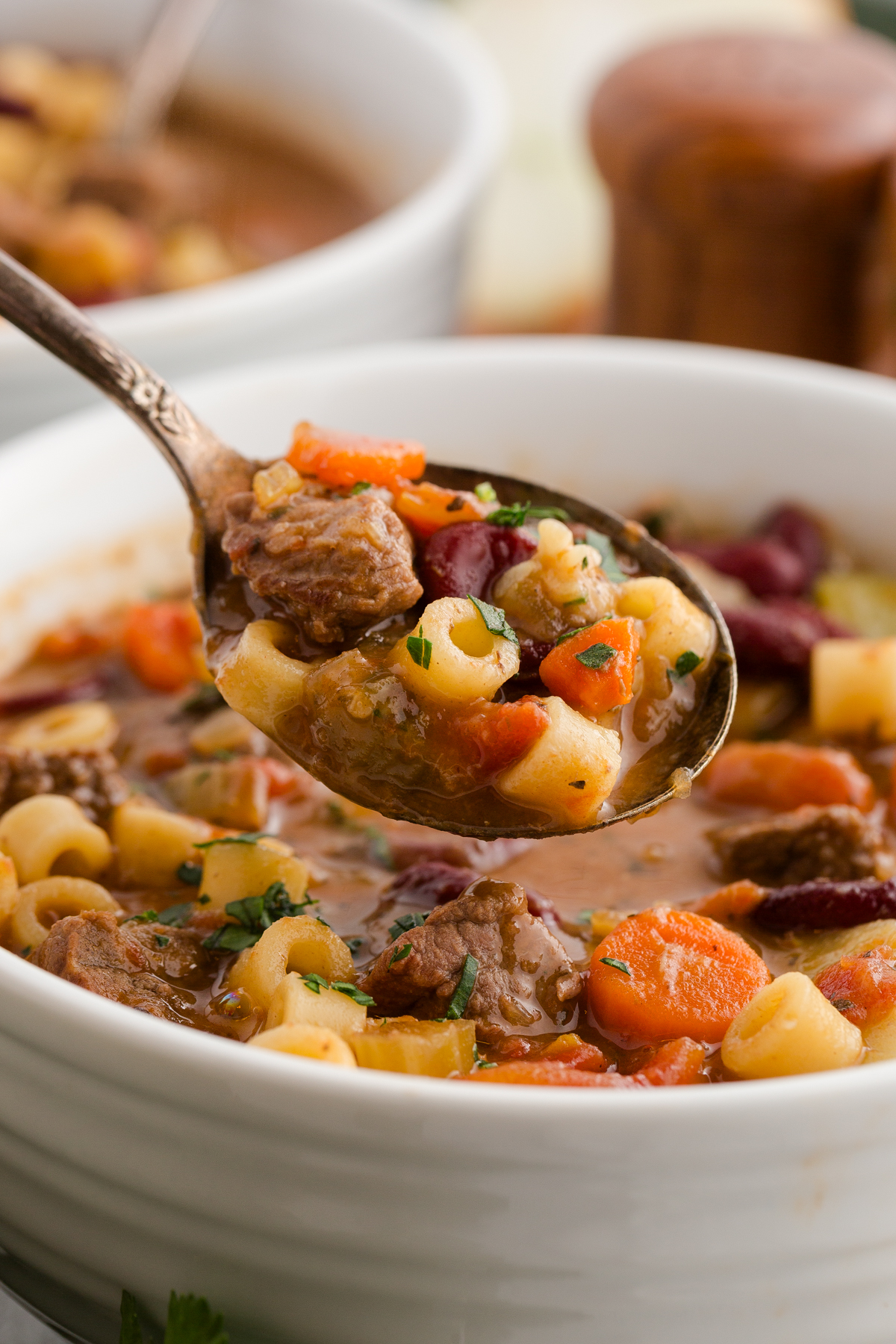 a spoonful of Italian beef minestrone soup served out of a white ceramic bowl