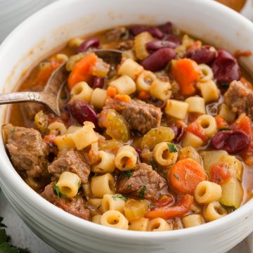 beef minestrone soup in a white bowl garnished with parsley