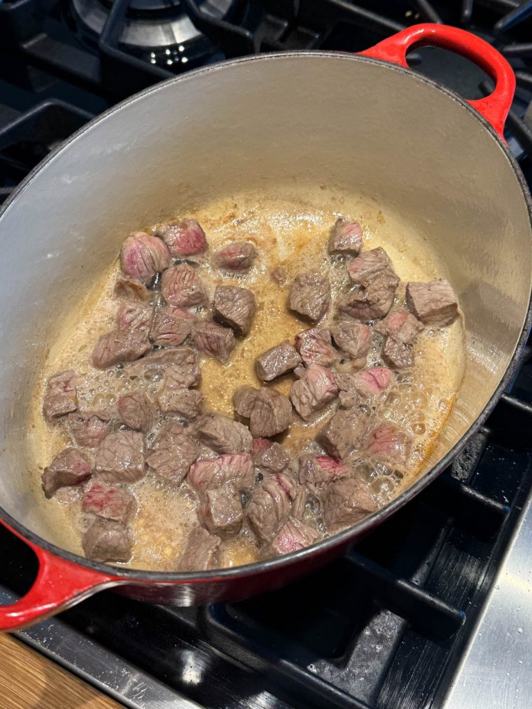 top sirloin cubed searing in a large Dutch oven pot