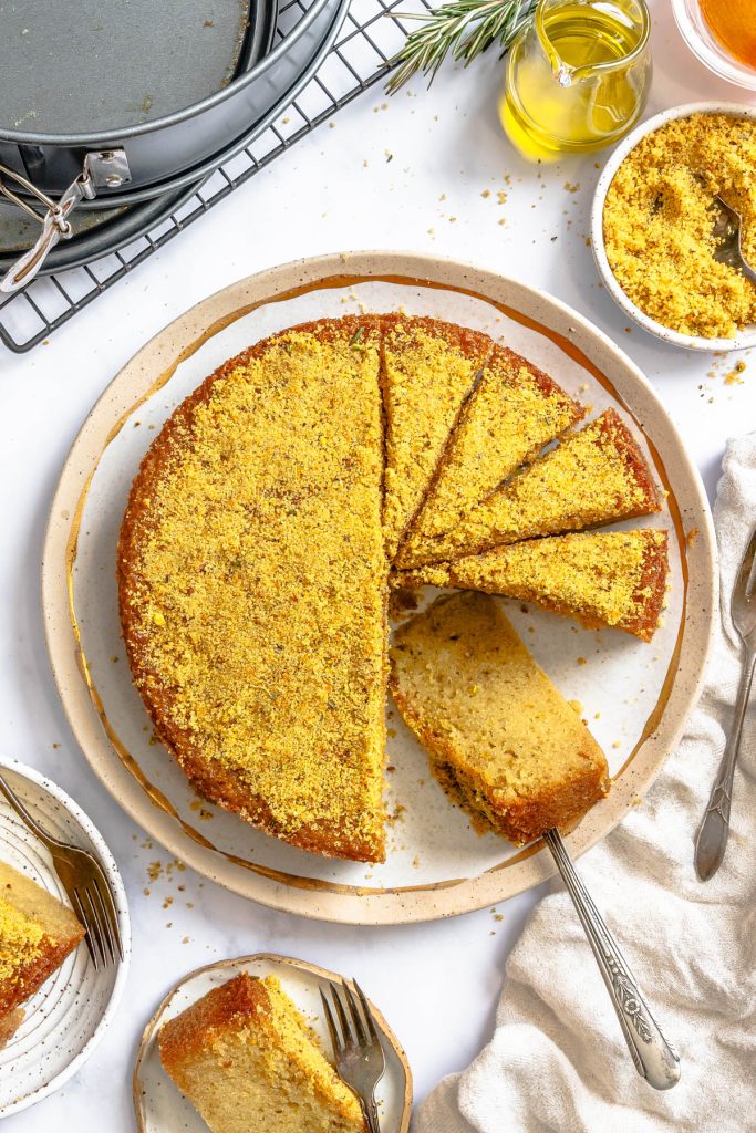 a sliced olive oil cake topped with a pistachio sugar topping on a platter