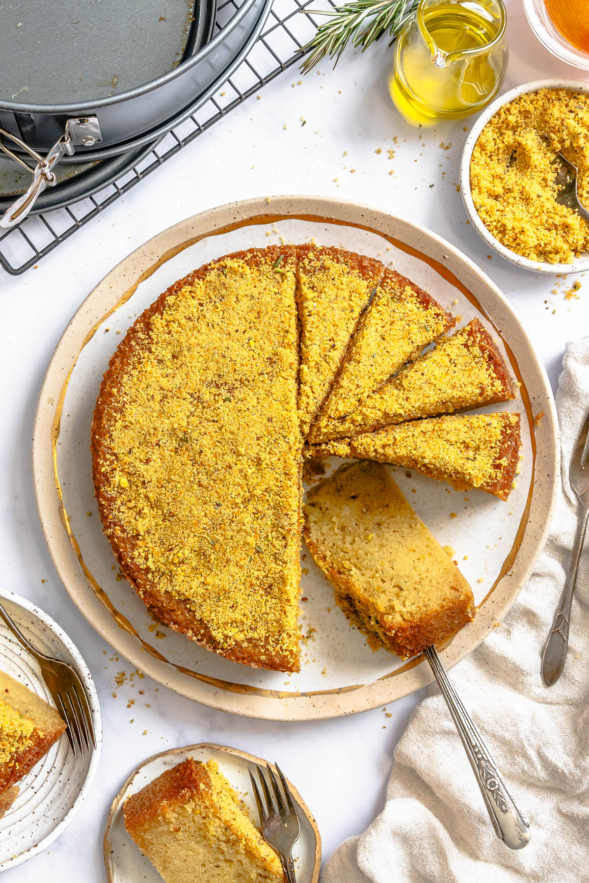 a sliced olive oil cake topped with a pistachio sugar topping on a platter