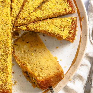 warm citrus olive oil cake sliced and set on a beige and gold rimmed plate
