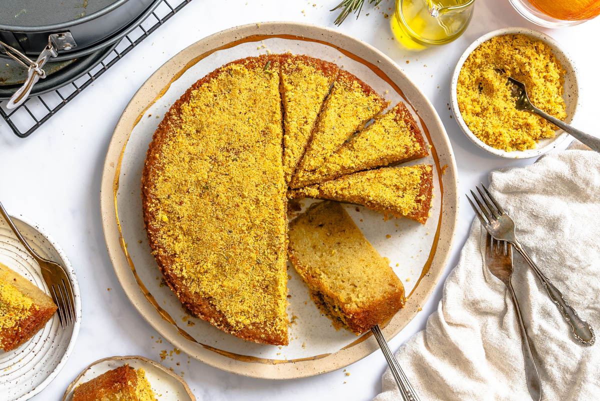 a half sliced citrus olive oil cake on a beige and gold rimmed platter