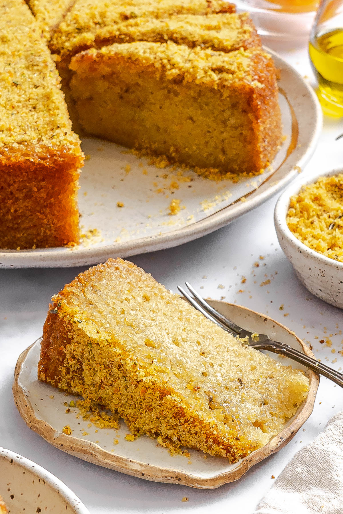 a slice of Italian olive oil cake topped with a sugar crumble topping on a small dessert plate