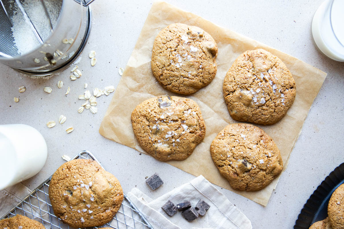 oat flour decadent chocolate chip cookies sprinkled with flaky salt and set on a piece of parchment paper
