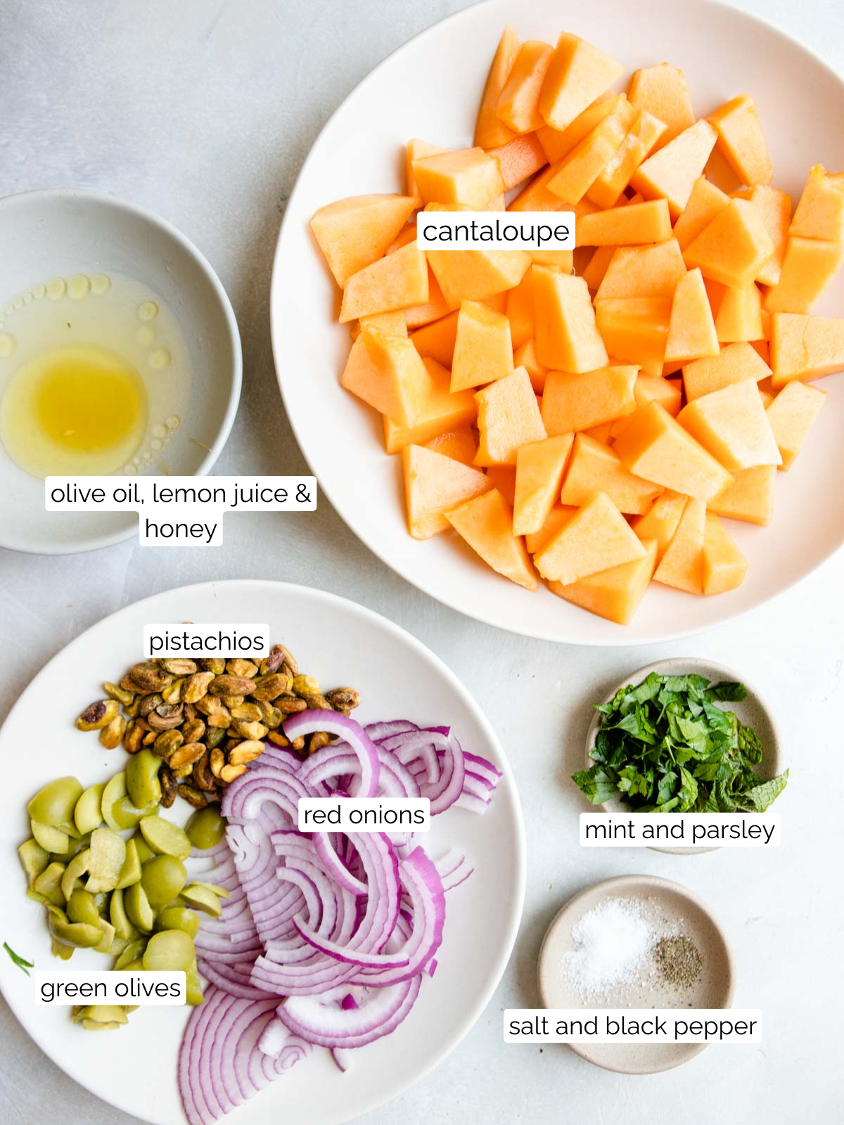ingredients to make a savory cantaloupe salad with green olives and pistachios