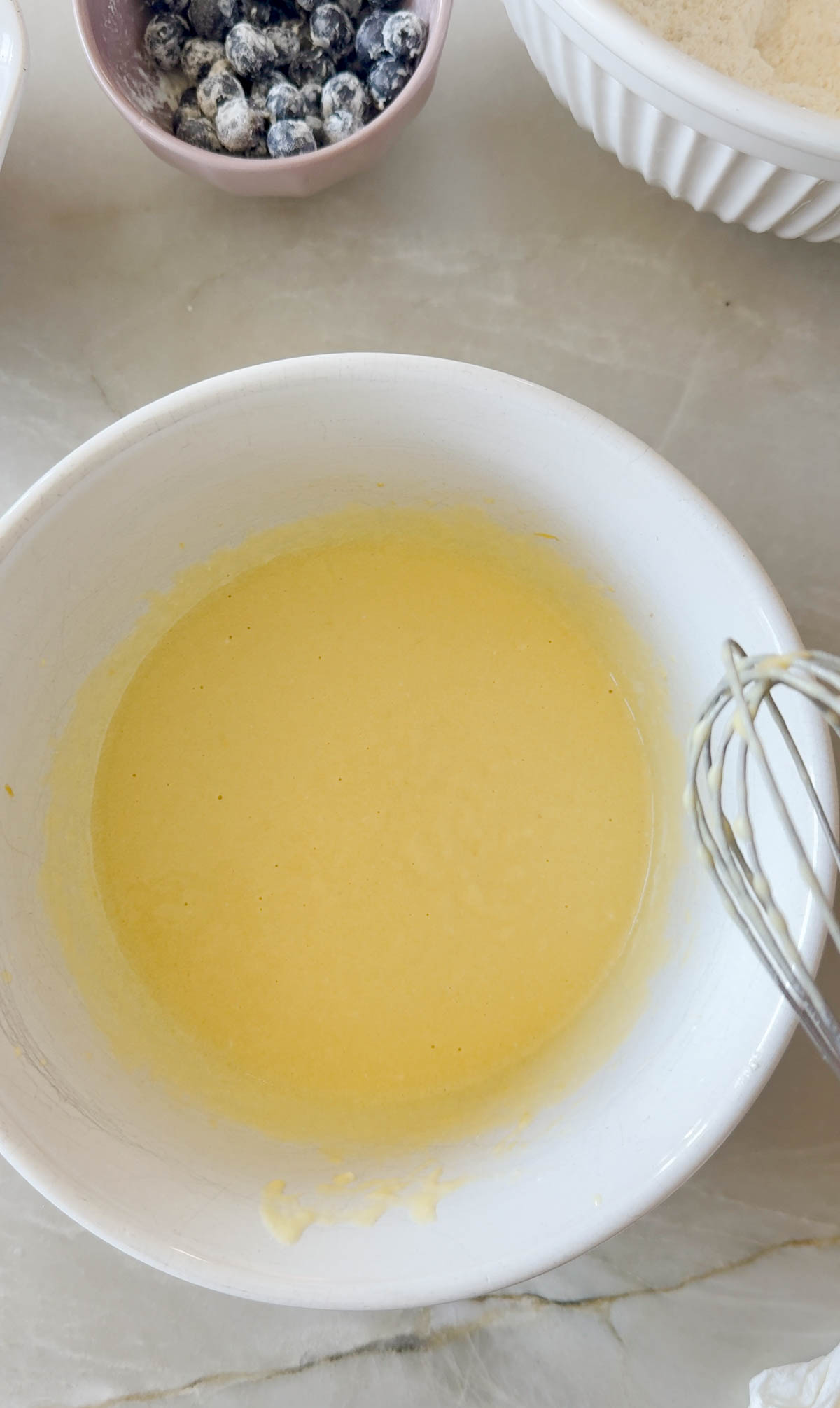 eggs and milk and olive oil in a white mixing bowl to make muffins