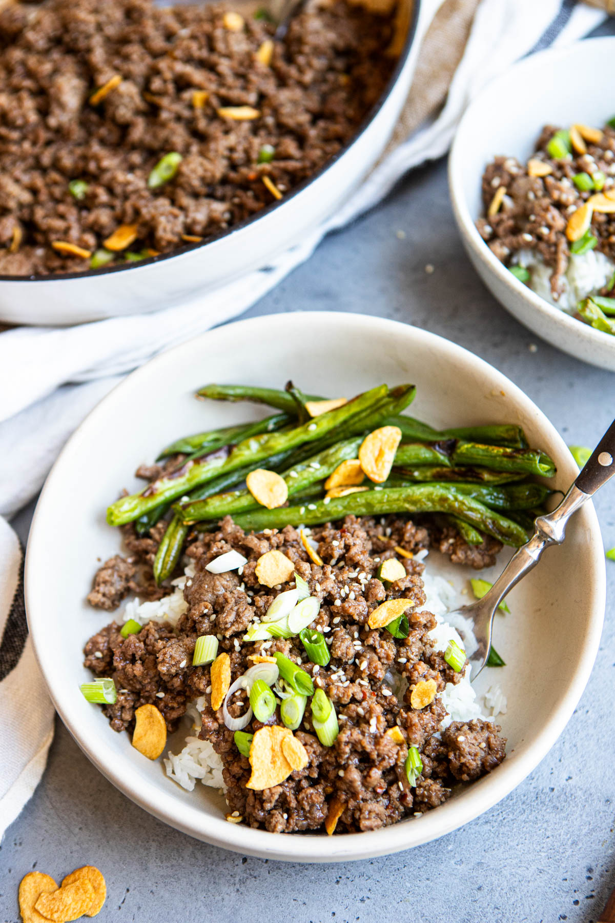 asian ground beef bowl on a bed of rice and served with roasted green beans