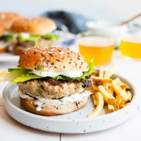 Greek turkey burger on a whole grain bun on a plate with french fries