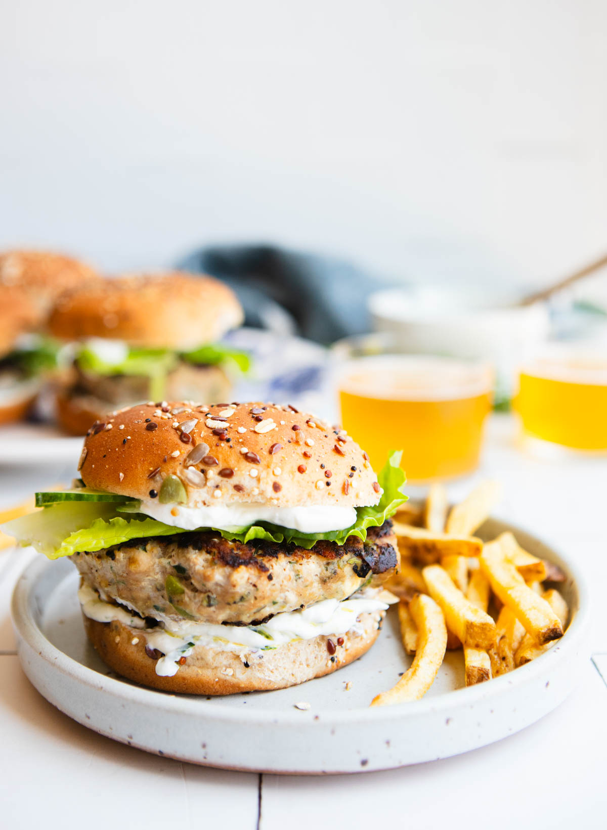 Greek turkey burger on a plate with french fries and a glass of beer in the background 
