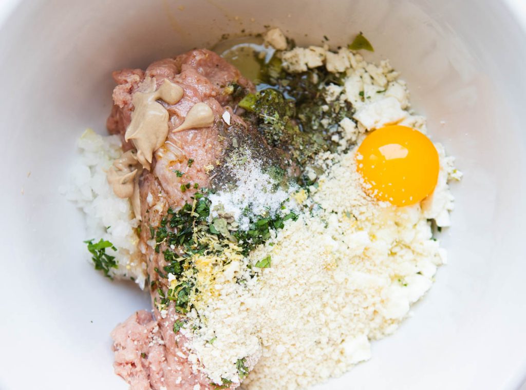 ingredients to make Greek turkey burgers in a large white ceramic bowl