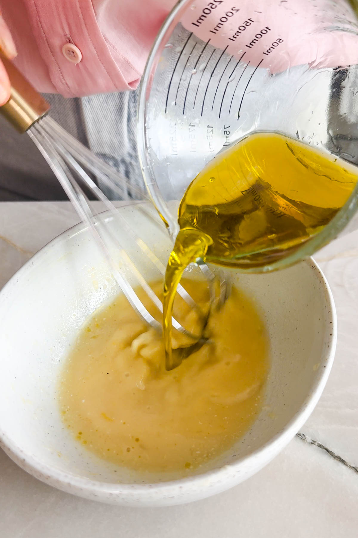 lemon vinaigrette being made in a white bowl
