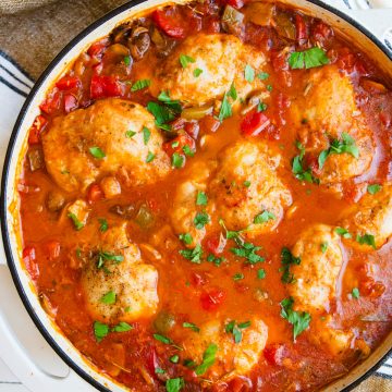 white enameled cast iron skillet with cooked chicken cacciatore