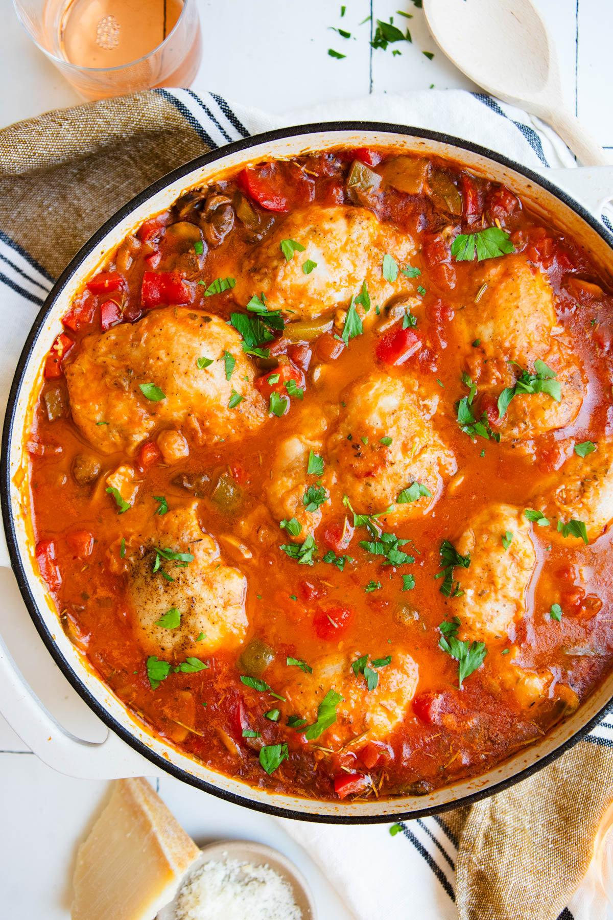 white enameled cast iron skillet with cooked chicken cacciatore