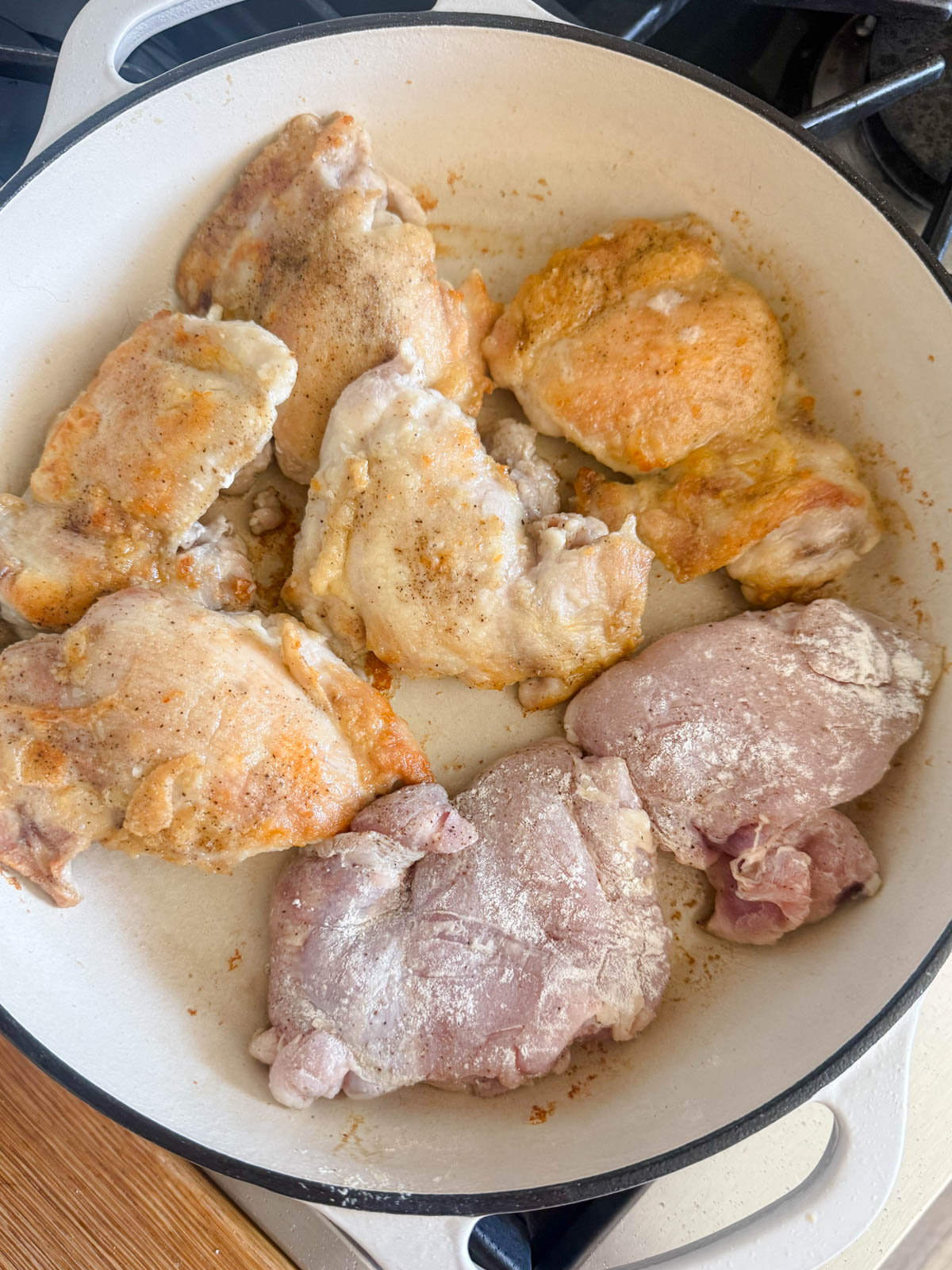 chicken thighs cooking in a large cast iron skillet