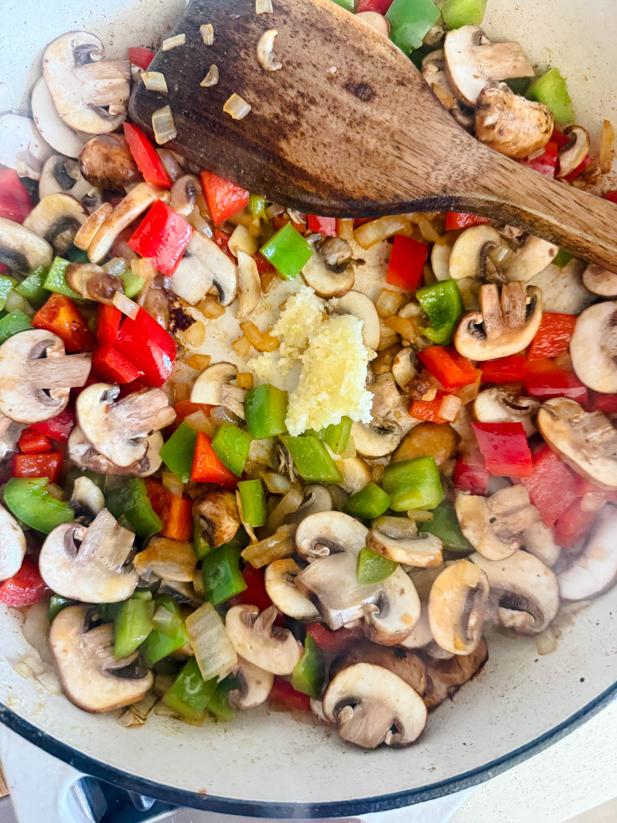 mushrooms and garlic added to a pan of veggies in a large saute pan