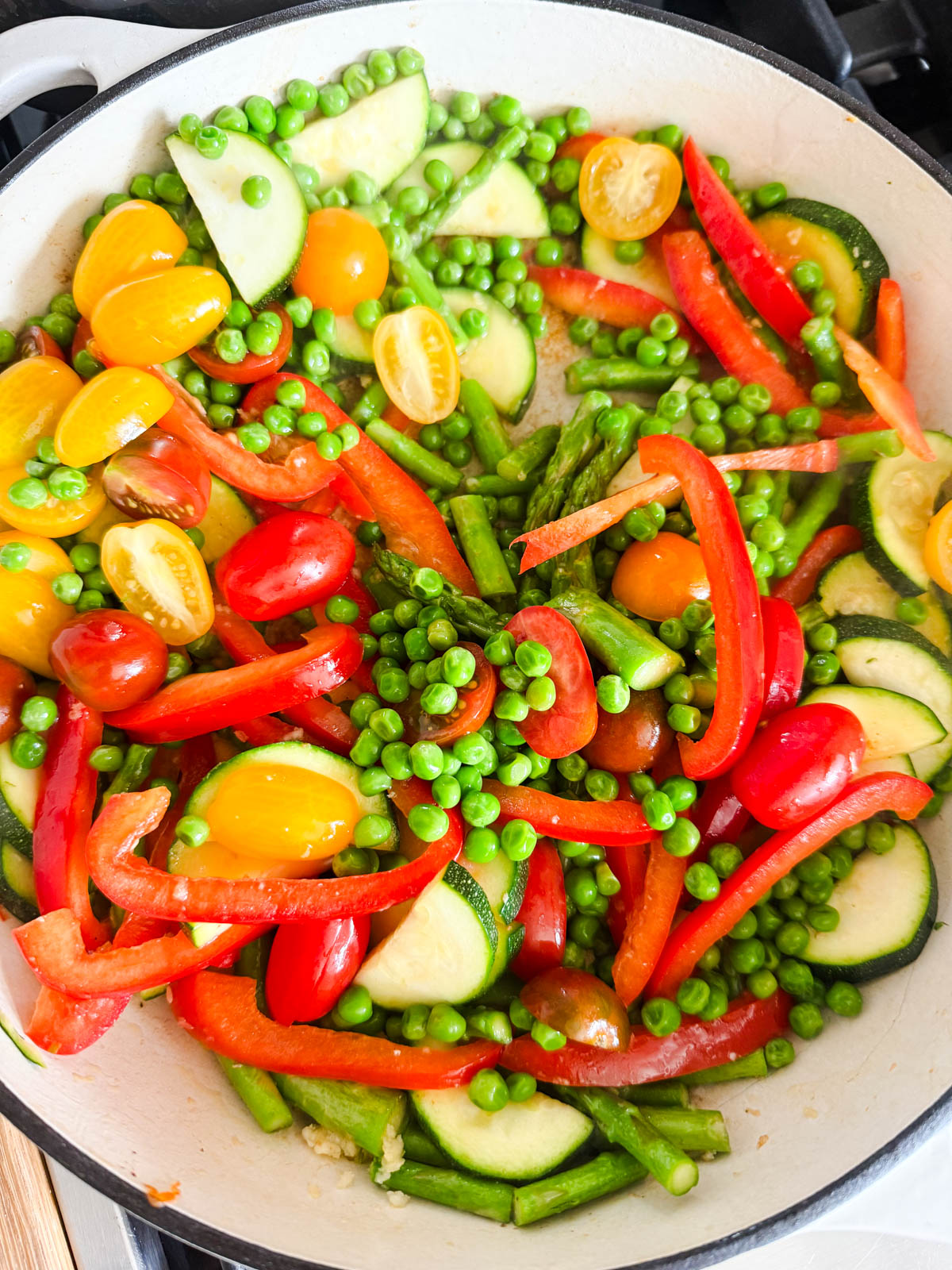 peas and tomatoes added to a pan filled with veggies