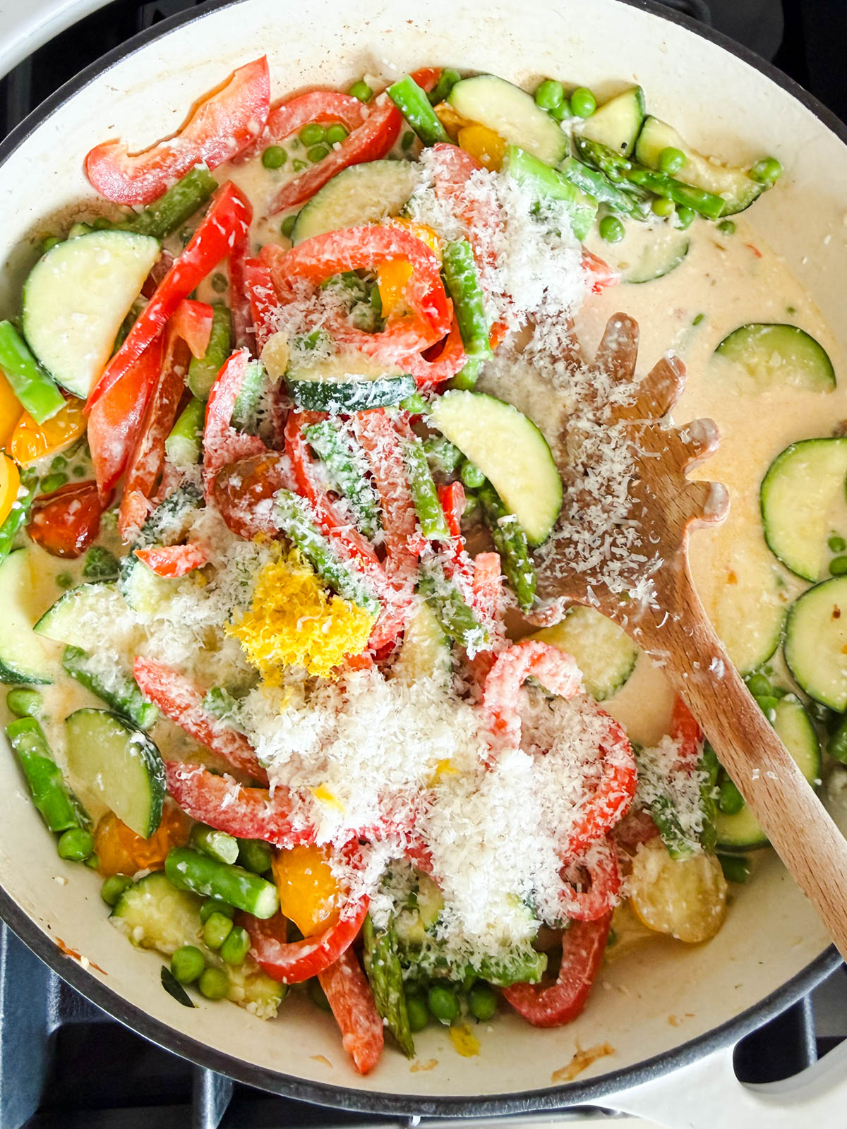 shrimp and parmesan cheese added to pan of shrimp primavera pasta