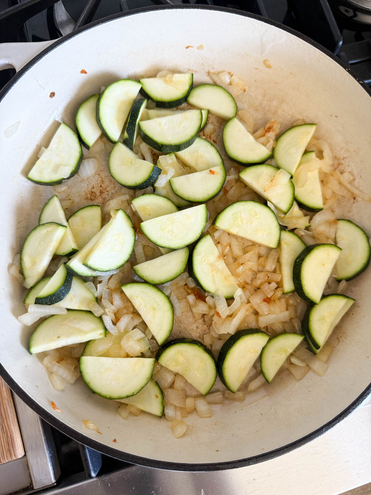 onions and zucchini sautéing in a pan