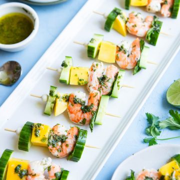 mango and shrimp skewers appetizer on a white ceramic tray