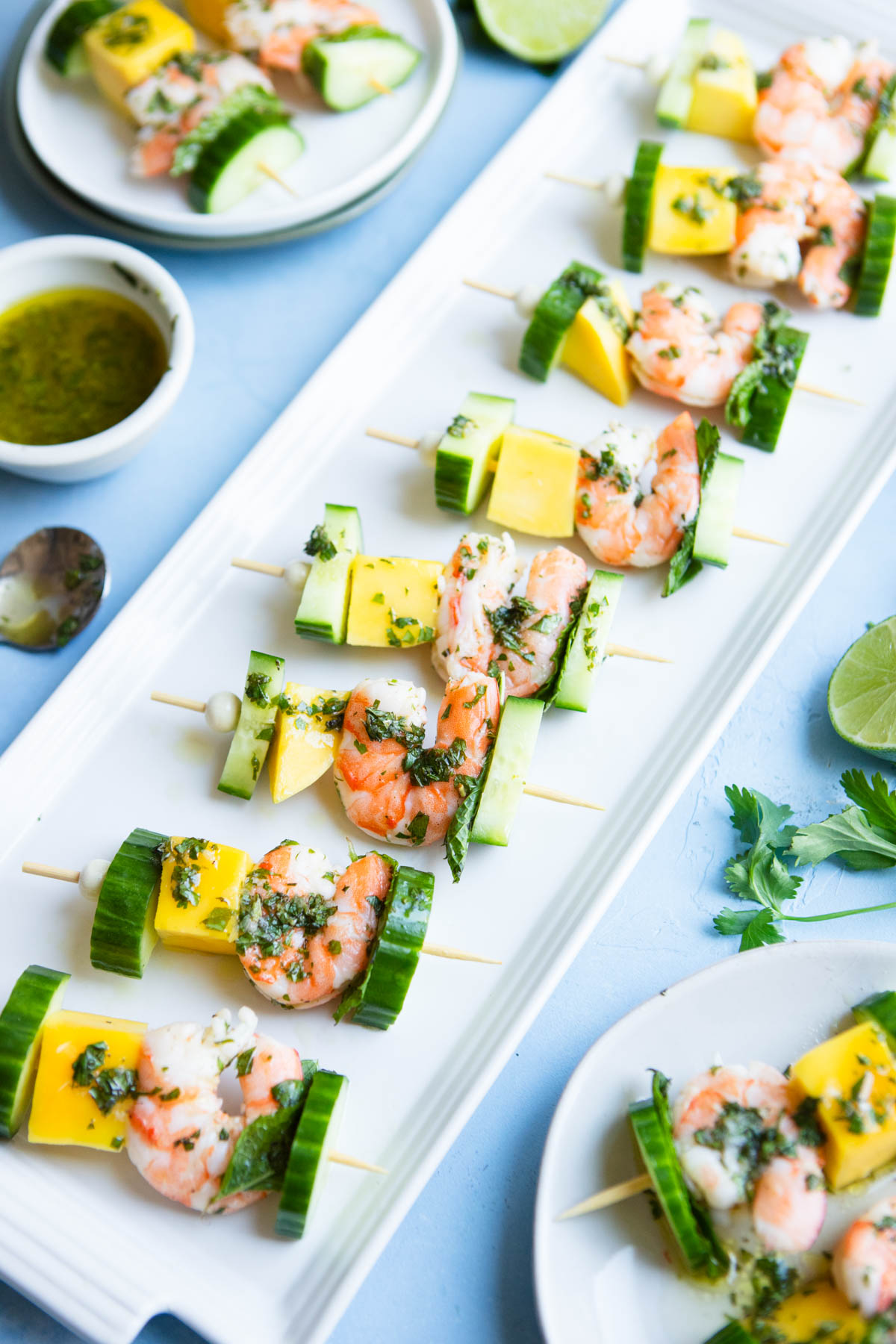 mango and shrimp skewers appetizer on a white ceramic tray