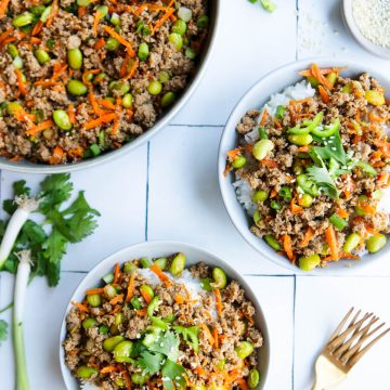 asian ground turkey rice bowls garnished with cilantro and sesame seeds in white ceramic bowls