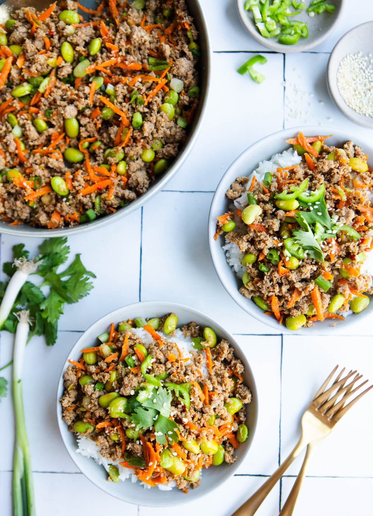 asian ground turkey rice bowls garnished with cilantro and sesame seeds in white ceramic bowls