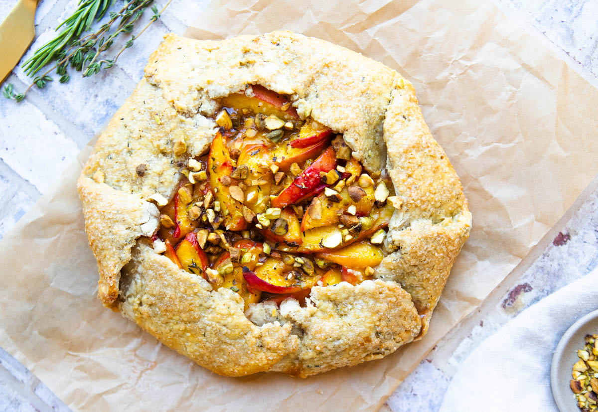 peach galette baked in the oven and cooling on a piece of parchment paper