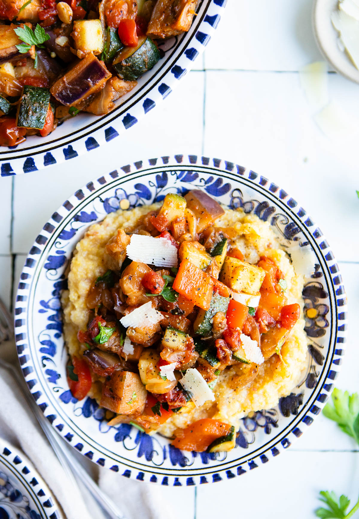 creamy polenta in a bowl served with eggplant ratatouille and garnished with parmesan cheese shavings