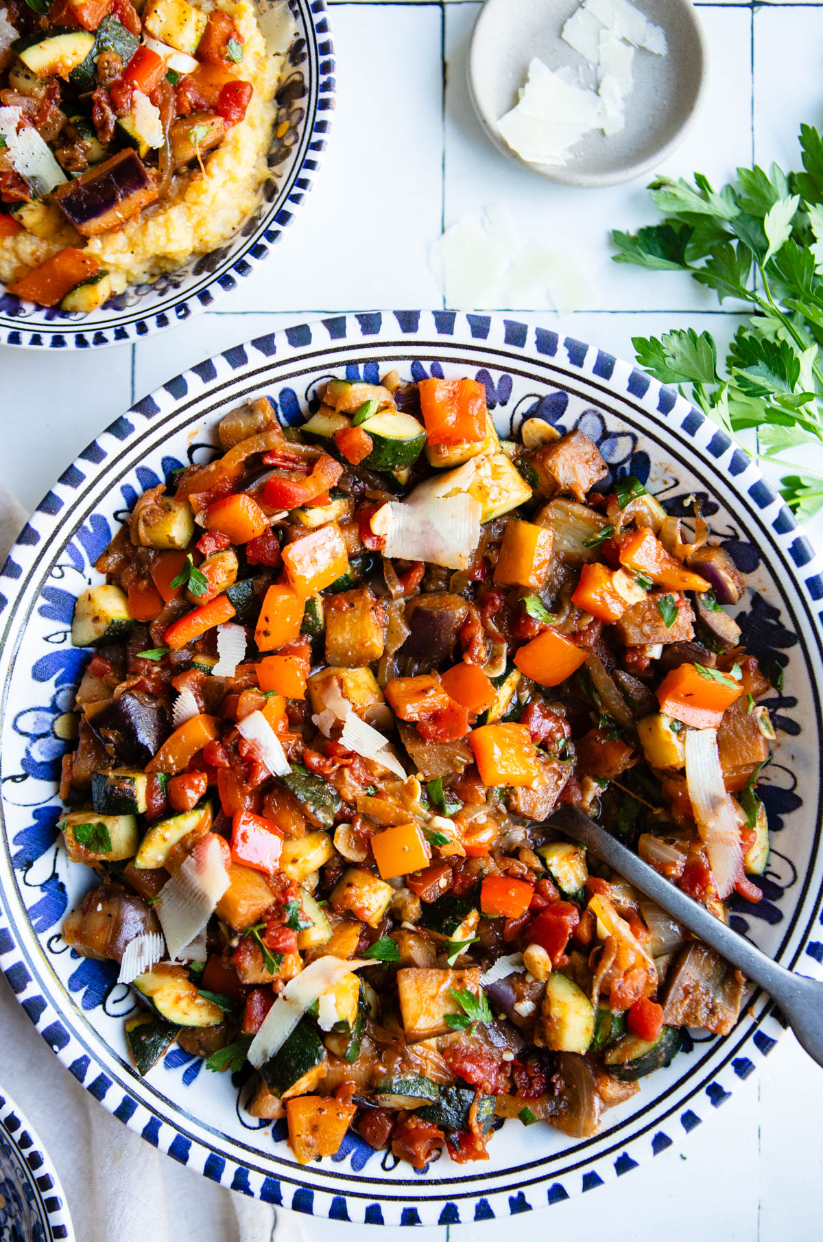 French ratatouille eggplant stew in a blue and white serving bowl topped with shaved parmesan cheese