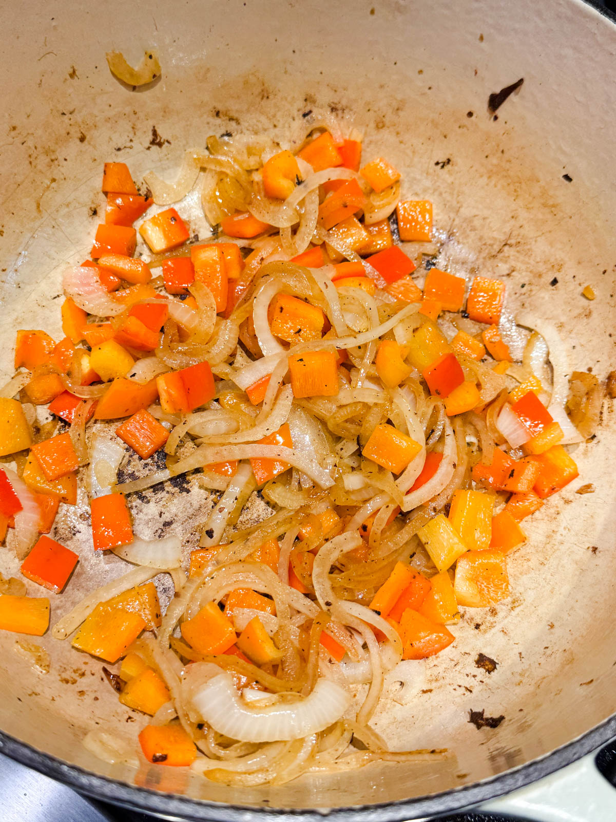 onions and peppers cooking in a large Dutch oven