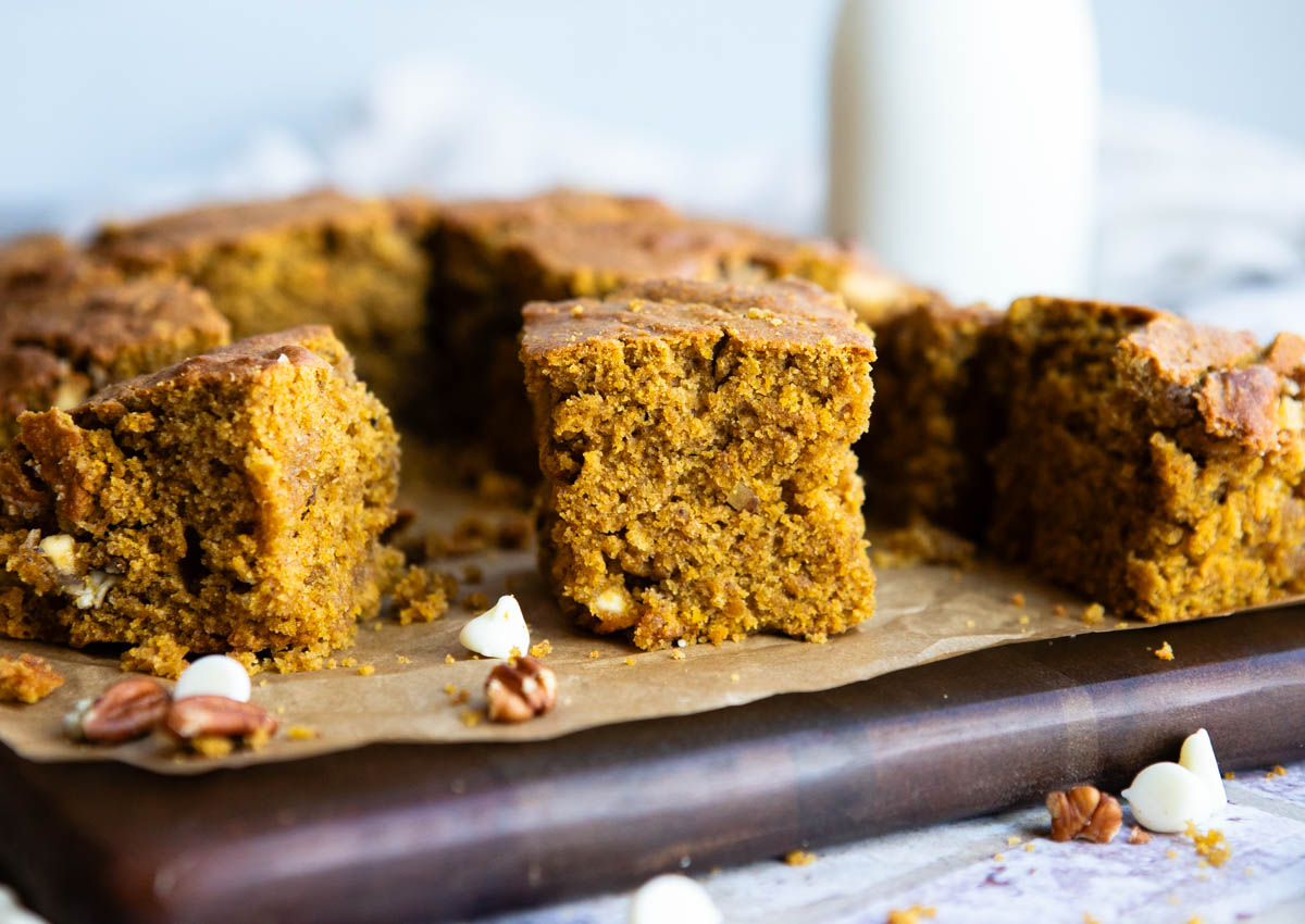 pumpkin bars with white chocolate chips and pecans on a wood cutting board
